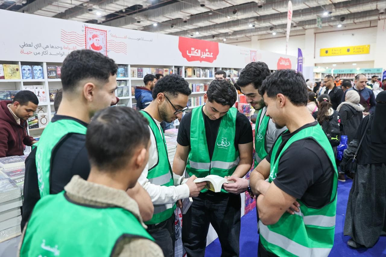 متطوعو مؤسسة رزق يطالعون كتابًا في أروقة معرض الكتاب