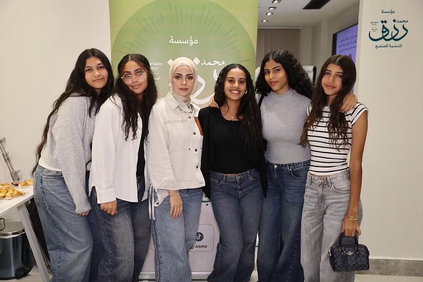 مشاركات من برنامج بناء قدرات الشباب أمام شعار المؤسسة